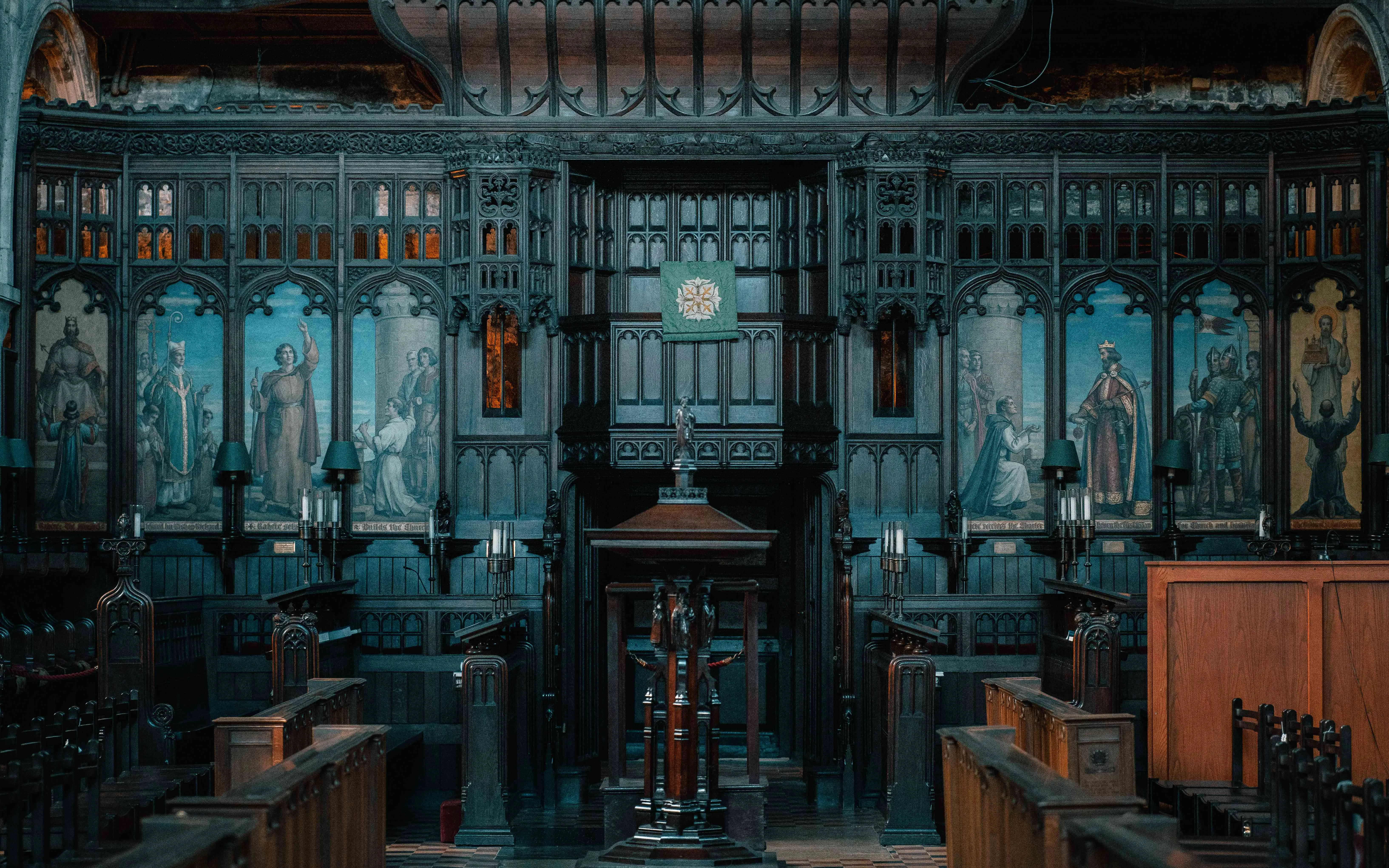 Ornate dark-wood choir screen and pulpit with painted panels inside St Bartholomew’s
