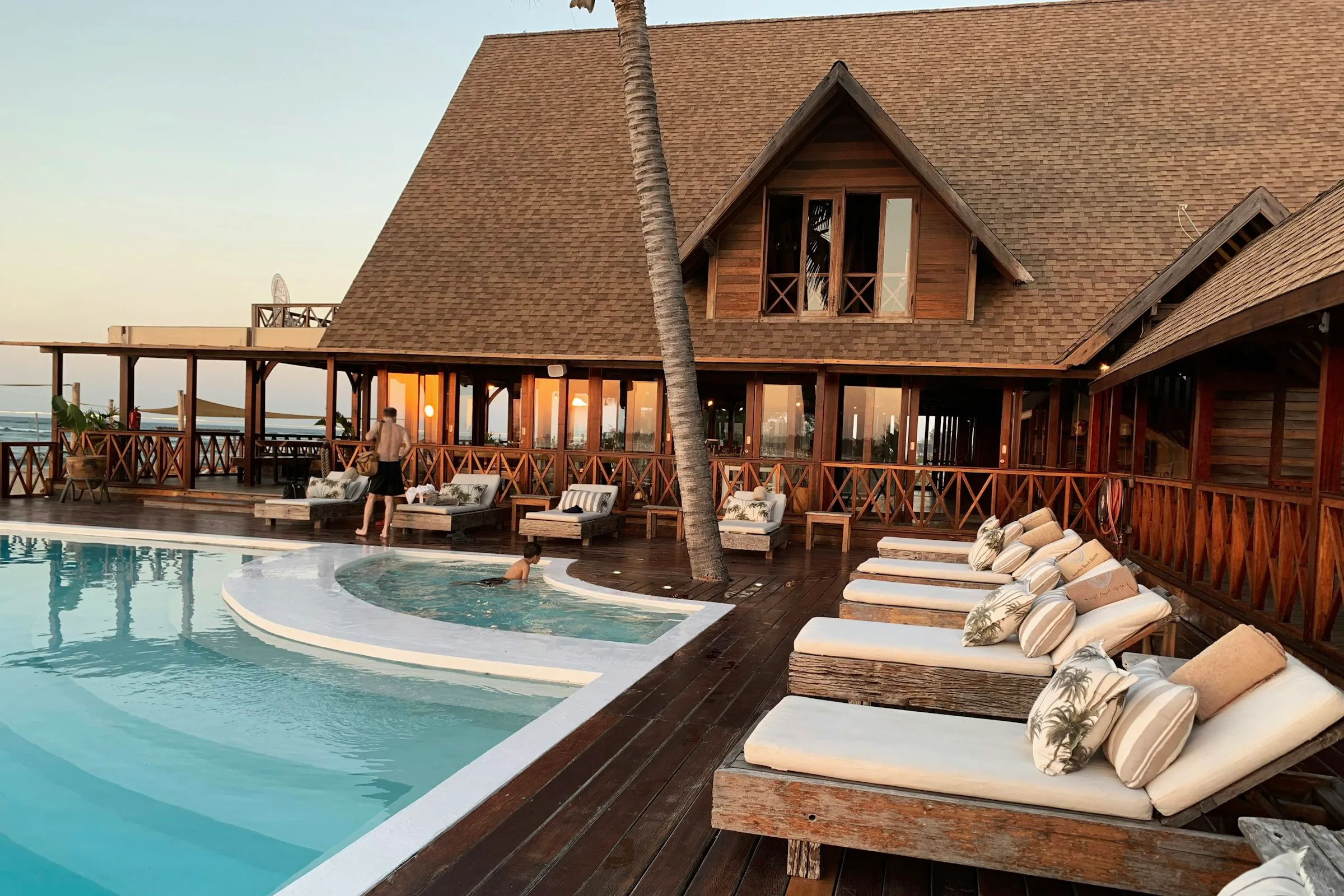 Resort pool deck and timber lodge lit up at dusk