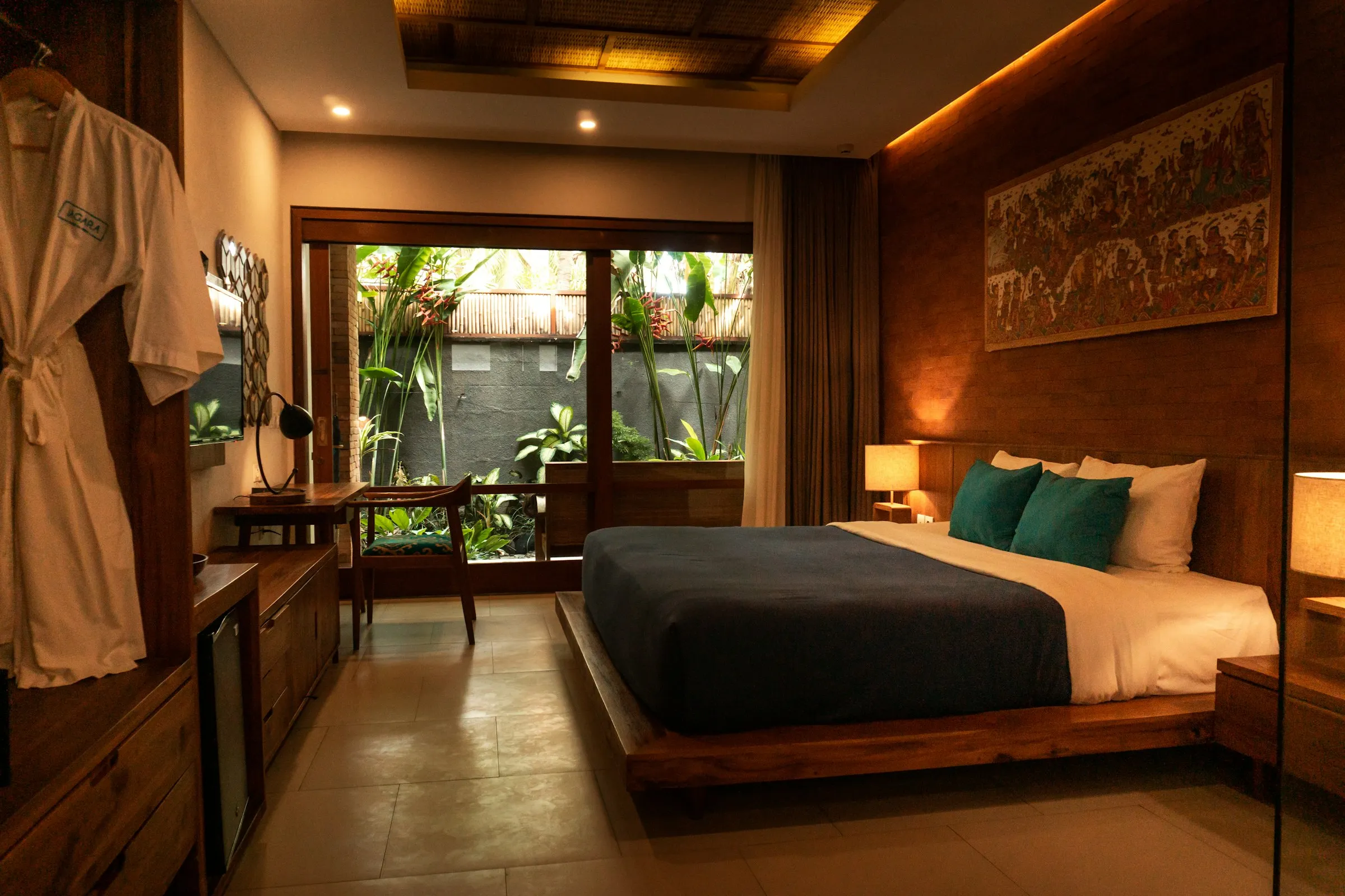 Warm wood-panelled hotel bedroom opening onto a tropical garden