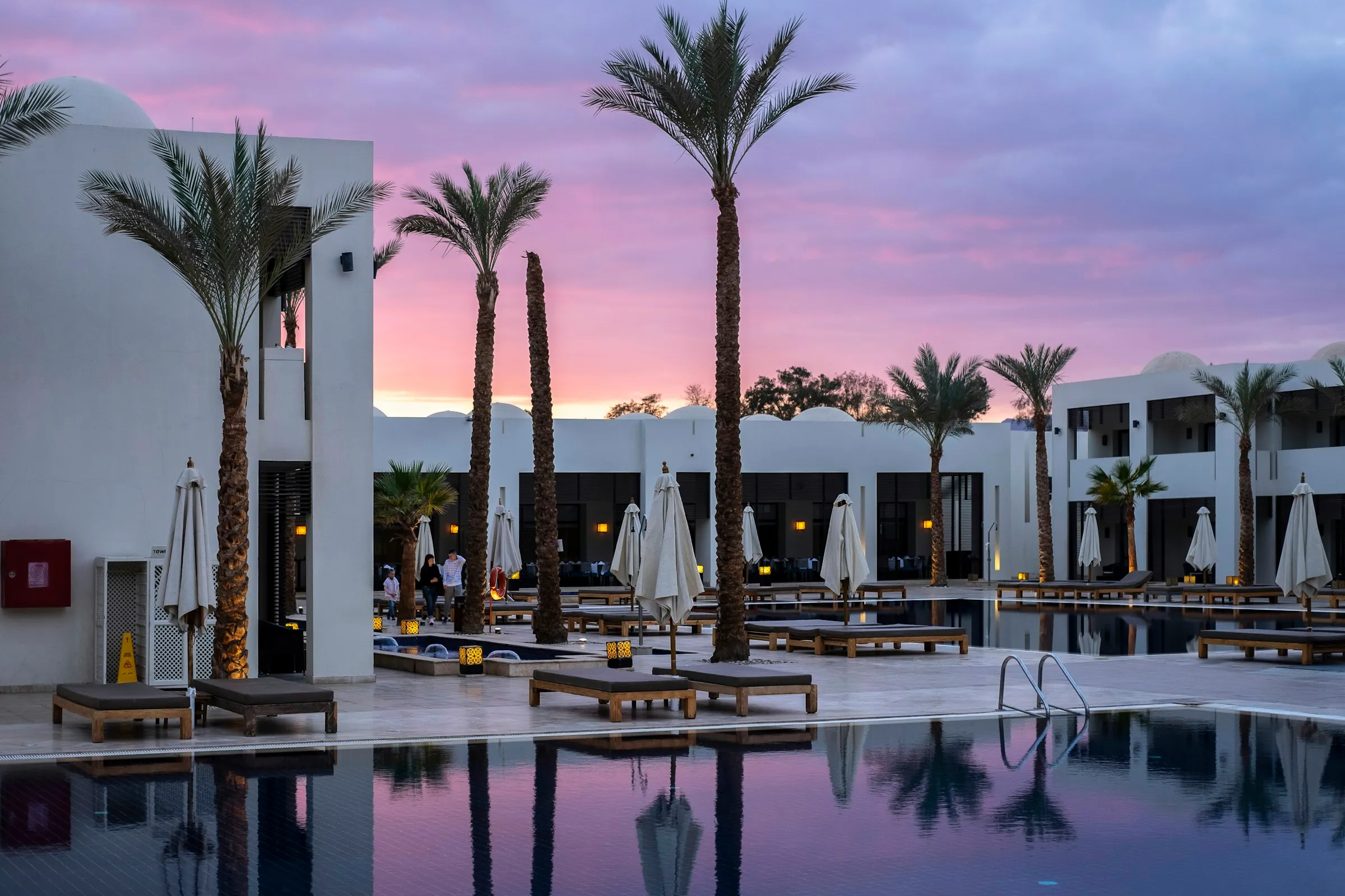 Courtyard pool reflecting purple twilight sky among white resort villas