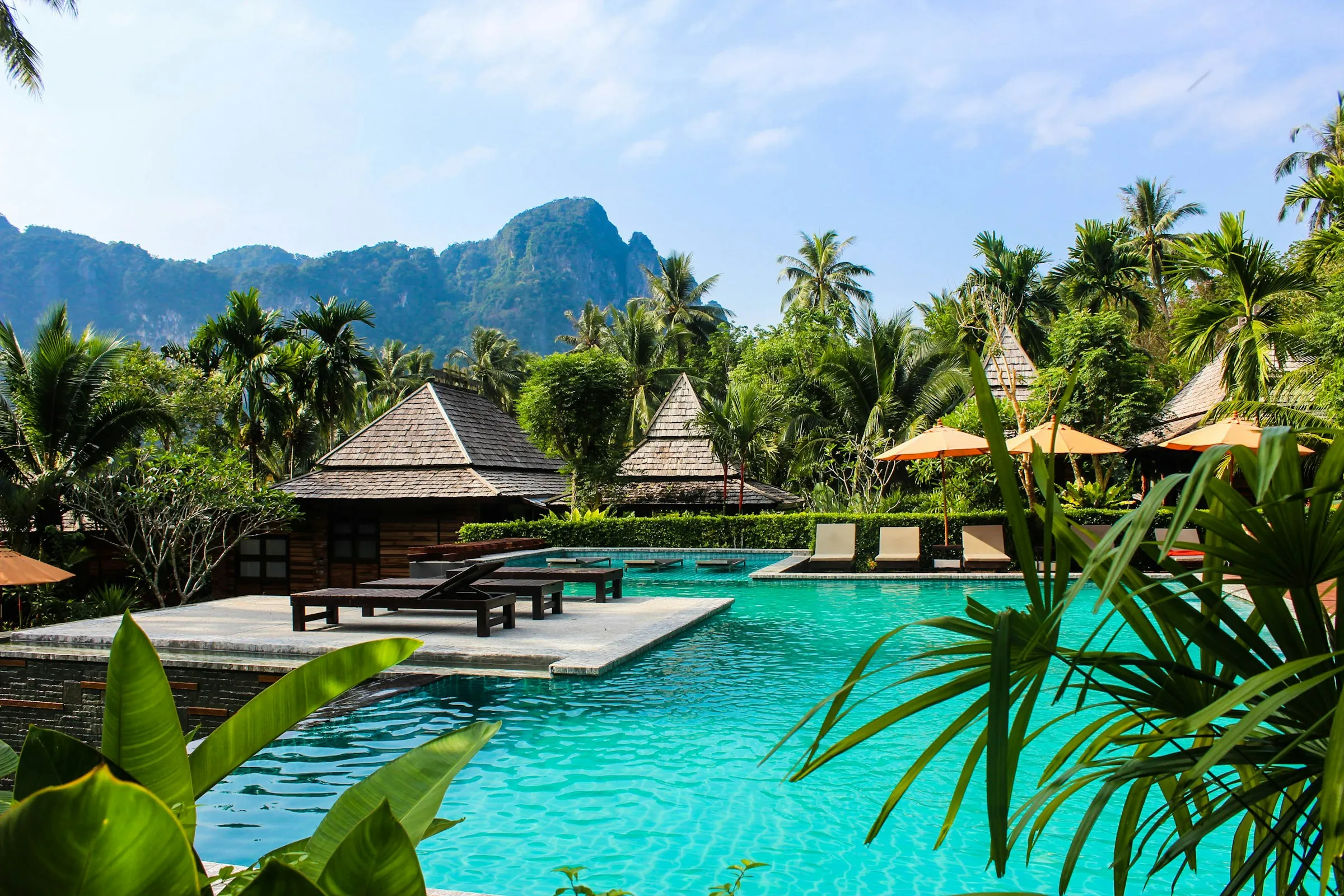 Tropical resort pool framed by palms with limestone mountains beyond